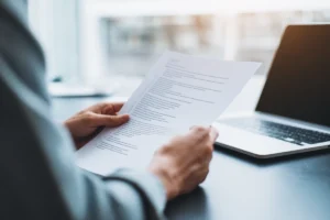 Person som granskar sitt CV vid ett skrivbord med laptop och anteckningar