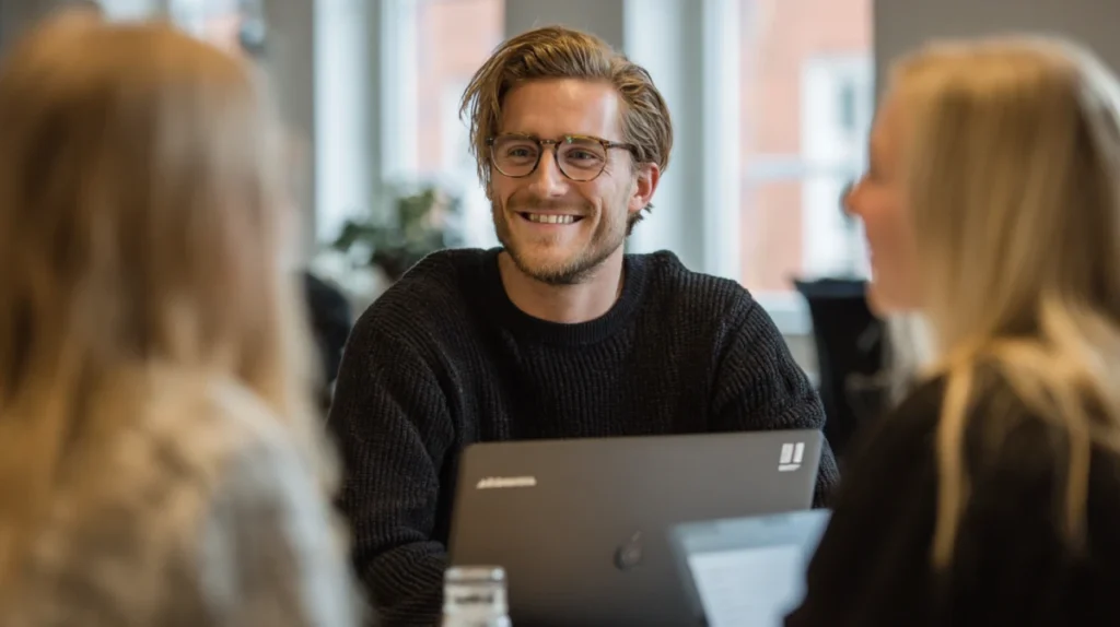 En bild som symboliserar en positiv företagskultur, med två kollegor i ett avslappnat samtal vid ett skrivbord.