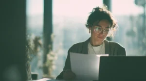 En person som noggrant granskar en enskild jobbansökan vid ett skrivbord, istället för en hög med papper.