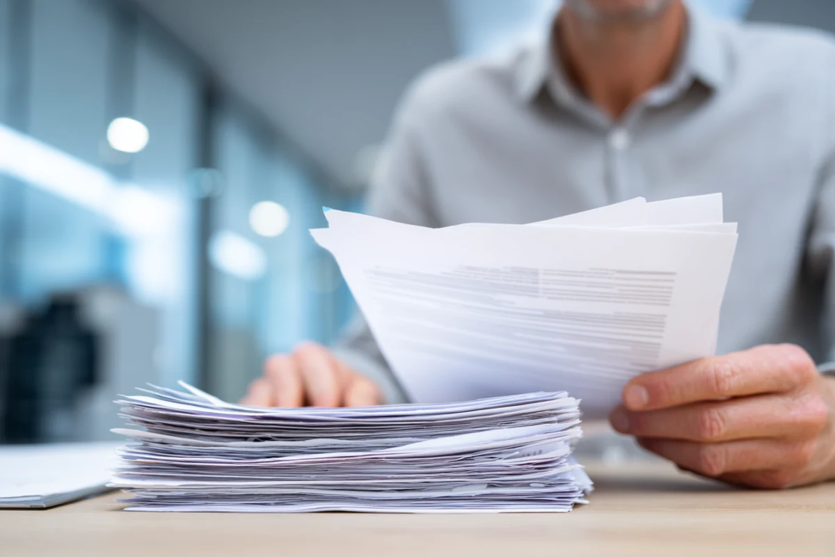 Rekryterare granskar ett CV vid skrivbord med flera utskrivna ansökningar