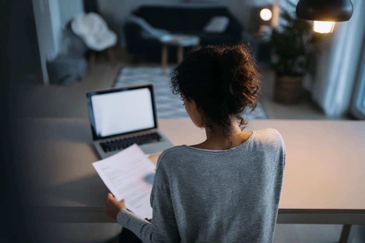 Person som sitter vid skrivbord framför laptop och granskar sitt CV inför en jobbansökan